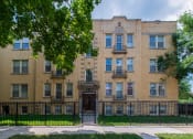 Thumbnail 1 of 13 - a large brick building with a black fence in front of it