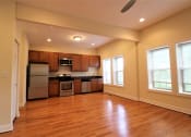 Thumbnail 4 of 13 - an empty kitchen with wood flooring and stainless steel appliances