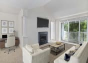 Thumbnail 3 of 20 - Bright living room with neutral-toned furniture, a fireplace with wall-mounted TV, home office setup, and large glass doors opening to a private balcony.