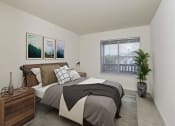 Thumbnail 5 of 20 - Minimalist bedroom with a wooden bed frame, stylish decor, and a large window offering natural light and balcony views.