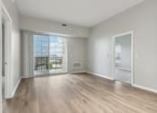 Thumbnail 6 of 42 - A spacious room with wooden flooring and a view of the city through the window.