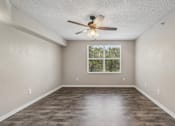 Thumbnail 28 of 40 - Bright living room with large window, wood-style flooring, and ceiling fan in a 1-bedroom apartment at Gregory Cove in Jacksonville, FL.