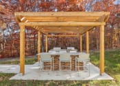 Thumbnail 16 of 20 - A wooden pergola with a grill and seating area in the middle of a grassy area.