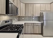 Thumbnail 4 of 42 - A modern kitchen with a stove, microwave, and refrigerator.