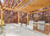 Thumbnail 17 of 20 - A wooden pergola with a grill and chairs is set up in a backyard.