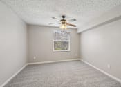 Thumbnail 30 of 40 - Carpeted bedroom with large window, ceiling fan, and neutral finishes in a 1-bedroom apartment at Gregory Cove in Jacksonville, FL.