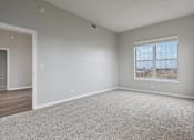 Thumbnail 9 of 42 - A spacious room with a large window and carpeted floor.