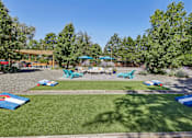 Thumbnail 22 of 26 - A sunny day at a park with a playground and picnic tables.