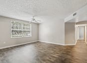 Thumbnail 6 of 40 - Bright living room with large window, wood-style flooring, and open floor plan in a 3-bedroom, 2-bath apartment at Gregory Cove in Jacksonville, FL.