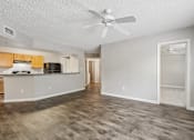 Thumbnail 2 of 40 - Open living room with wood-style flooring, ceiling fan, kitchen breakfast bar, and bedroom access in a 3-bedroom, 2-bath apartment at Gregory Cove in Jacksonville, FL.