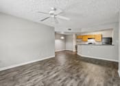 Thumbnail 5 of 40 - Spacious open-concept living room with wood-style flooring, breakfast bar, ceiling fan, and kitchen in a 3-bedroom, 2-bath apartment at Gregory Cove in Jacksonville, FL.