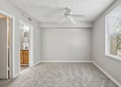 Thumbnail 8 of 40 - Carpeted primary bedroom with ceiling fan, large window, and en-suite bathroom access in a 3-bedroom, 2-bath apartment at Gregory Cove in Jacksonville, FL.