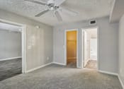 Thumbnail 9 of 40 - Spacious carpeted primary bedroom with walk-in closet, en-suite bathroom access, and ceiling fan in a 3-bedroom, 2-bath apartment at Gregory Cove in Jacksonville, FL.