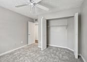 Thumbnail 11 of 40 - Carpeted bedroom with large closet, ceiling fan, and neutral finishes in a 3-bedroom, 2-bath apartment at Gregory Cove in Jacksonville, FL.