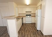 Thumbnail 10 of 26 - Open kitchen with wood-like flooring and white appliances at Canon de Arrowhead in Albuquerque, New Mexico