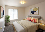Thumbnail 5 of 26 - A bedroom with a bed, nightstand, and a painting on the wall.