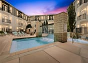 Thumbnail 23 of 25 - a swimming pool with a fountain in front of an apartment building