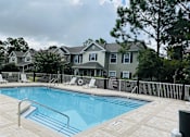 Thumbnail 4 of 17 - A pool surrounded by a black fence and a building in the background.