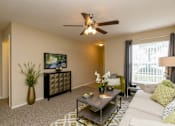 Thumbnail 7 of 17 - A living room with a white couch, a coffee table, and a ceiling fan.