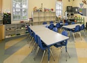 Thumbnail 9 of 17 - A classroom with tables and chairs and a whiteboard.