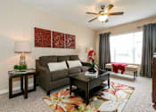 Thumbnail 15 of 17 - A living room with a brown couch, a coffee table, and a ceiling fan.