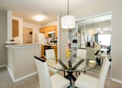 Thumbnail 16 of 17 - A modern kitchen with a glass dining table and white chairs.