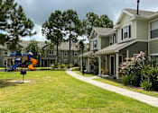 Thumbnail 1 of 17 - A playground with a slide and a swing set in front of a building.