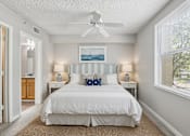 Thumbnail 16 of 44 - A bedroom with a white bed and a ceiling fan.