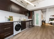 Thumbnail 2 of 18 - a kitchen with a washer and dryer and a living room with a door