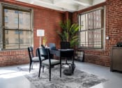 Thumbnail 6 of 18 - a dining room with a table and chairs in front of a brick wall