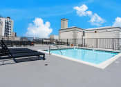 Thumbnail 13 of 18 - the pool on the rooftop of a building with chairs and a fence