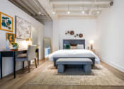 Thumbnail 7 of 18 - a bedroom with a bed and a desk with a chair