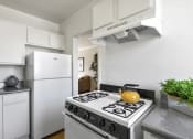 Thumbnail 3 of 20 - a white kitchen with a stove and a yellow kettle
