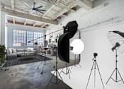 Thumbnail 42 of 57 - A photography studio with a ceiling fan, lighting equipment, and a couch.