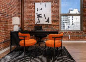 Thumbnail 7 of 21 - a brick walled office with a desk and orange chairs