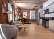 Thumbnail 3 of 21 - an open living room with a kitchen and a exposed brick wall