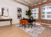 Thumbnail 9 of 21 - a living room with a table and chairs in front of a brick wall