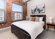 Thumbnail 10 of 21 - a bedroom with a bed and a brick wall
