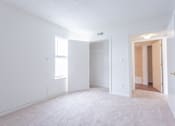 Thumbnail 23 of 52 - A white room with a carpeted floor and a door on the right side.