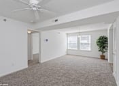 Thumbnail 6 of 52 - A room with a ceiling fan and a carpeted floor.