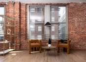 Thumbnail 9 of 19 - a living room with chairs and a brick wall