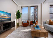 Thumbnail 3 of 19 - a living room with a couch and a table and a tv