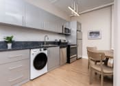 Thumbnail 6 of 19 - a kitchen with a washing machine and a table with a chair