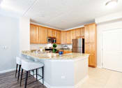 Thumbnail 27 of 42 - A kitchen with a white island and wooden cabinets.