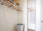 Thumbnail 20 of 42 - A white wall with a wooden hanger and a white trash can.