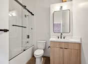 Thumbnail 18 of 57 - A white toilet sits next to a sink in a modern bathroom.