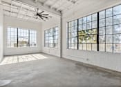 Thumbnail 20 of 57 - A large, empty room with a ceiling fan and large windows.
