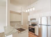 Thumbnail 1 of 13 - A kitchen with a marble countertop and stainless steel appliances.