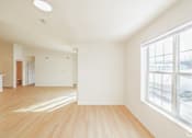 Thumbnail 4 of 13 - A large empty room with wooden floors and a window overlooking a snowy landscape.