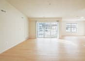 Thumbnail 7 of 13 - A large empty room with wooden floors and a glass door leading outside.